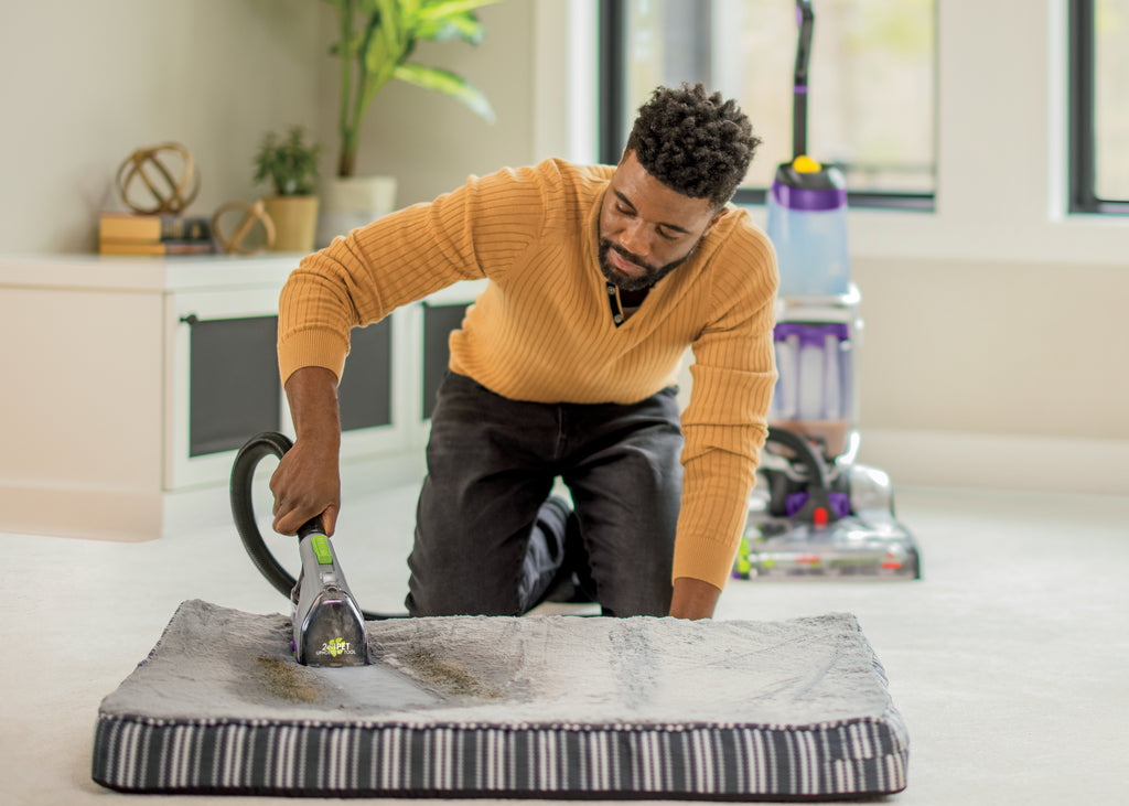 Man using Portable Carpet Cleaner to clean pet bed.