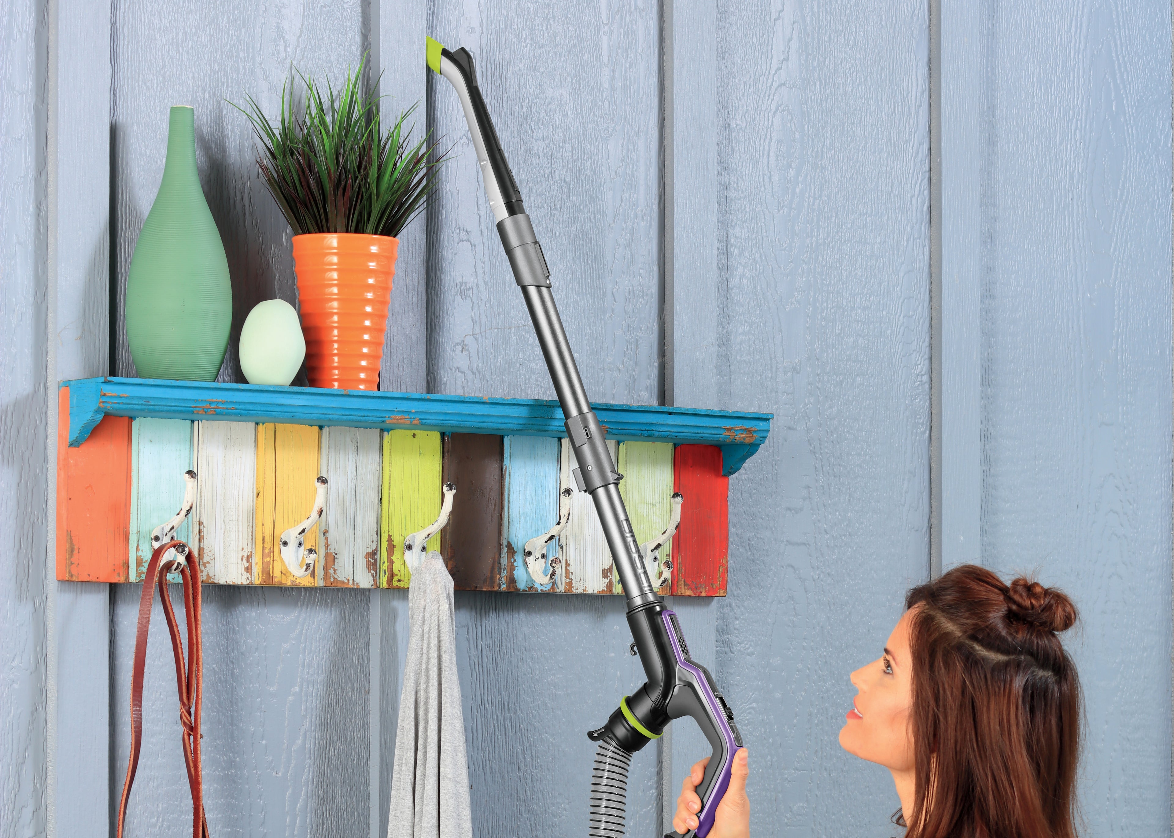 Woman using Pet Hair Eraser® Turbo Plus with Extension
                        Wand to Vacuum high on a wall