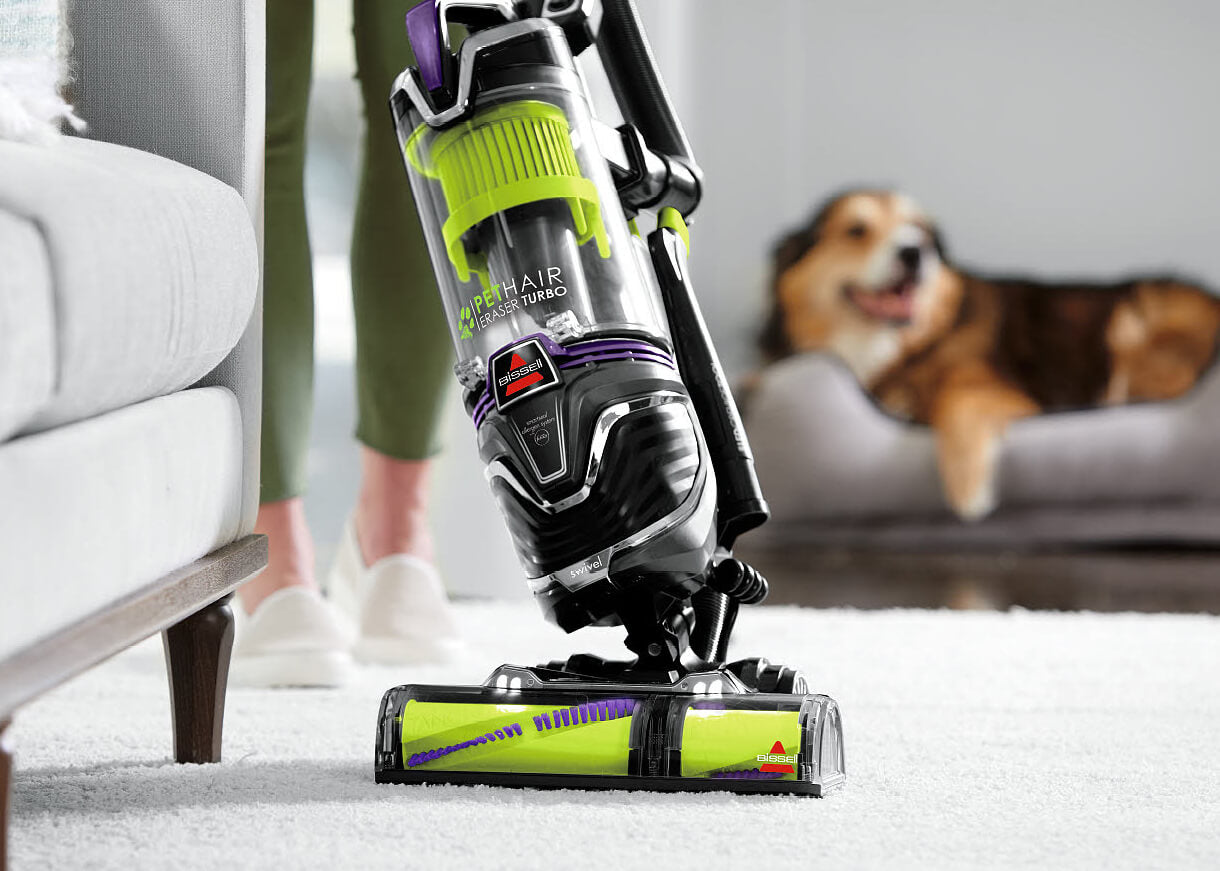 Pet Hair Eraser Turbo Plus vacuuming carpet around furniture.