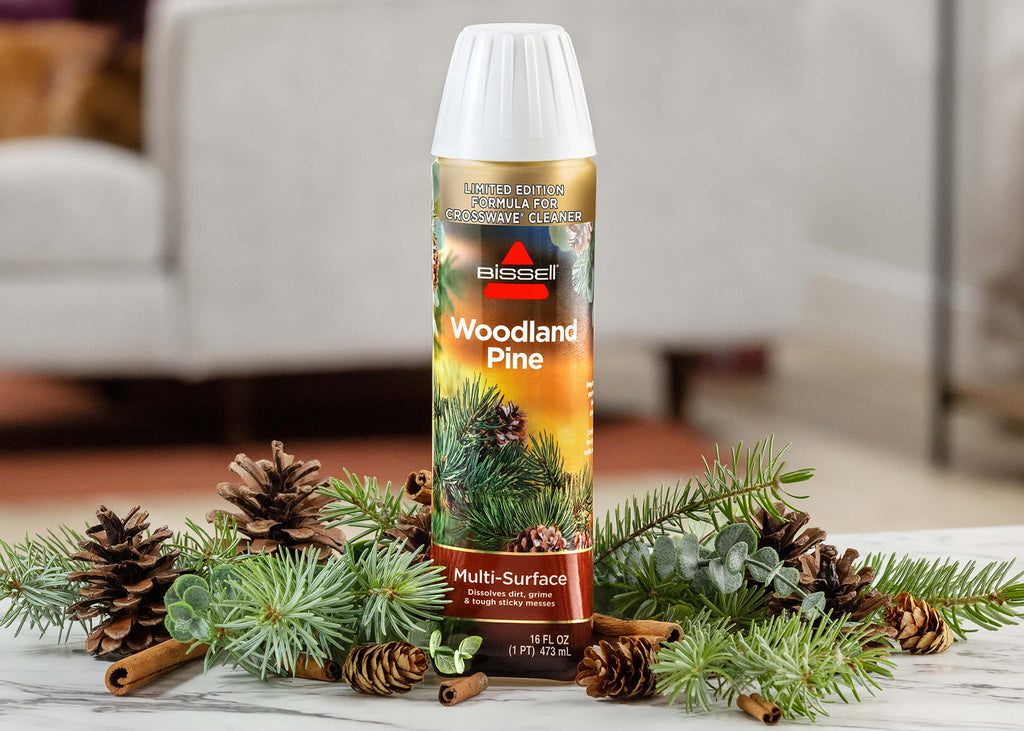 Bottle of Woodland Pine Formula surrounded by pine
                        cones and pine twigs