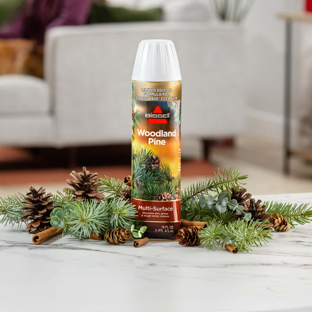 Bottle of Woodland Pine Formula surrounded by pine
                        cones and pine twigs