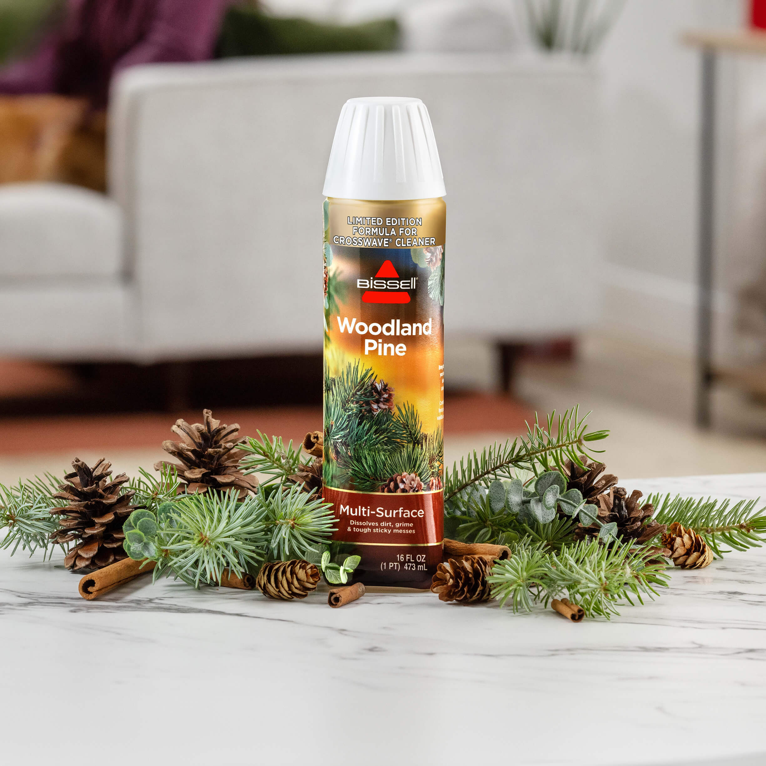 Bottle of Woodland Pine Formula surrounded by pine
                        cones and pine twigs