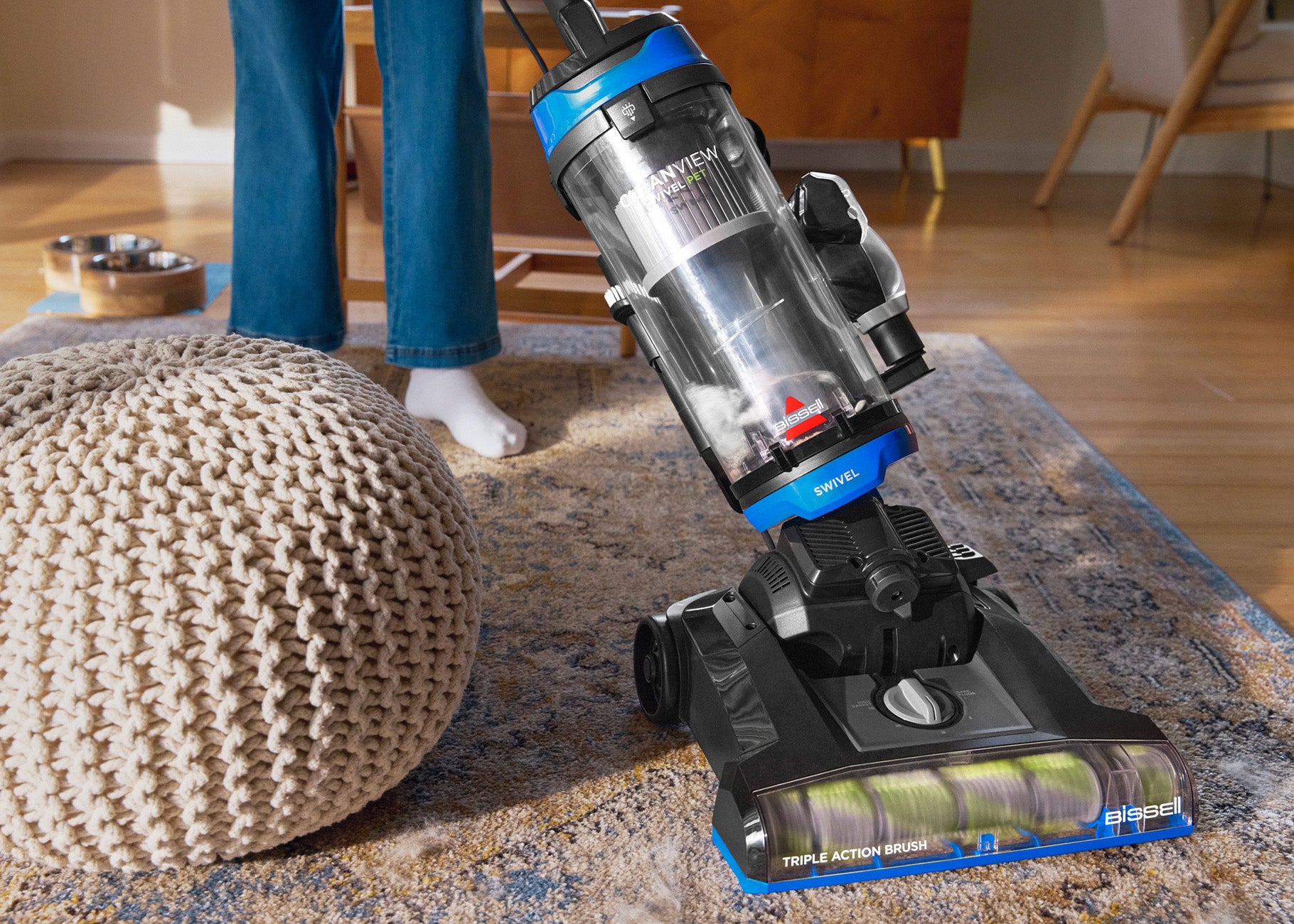 Vacuuming area rug around furniture showing swivel feature