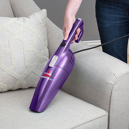 Woman Using FeatherWeight™ Lightweight Stick Vacuum in
                        Handheld Mode to Vacuum Chair