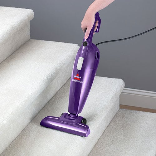 Woman Using FeatherWeight™ Lightweight Stick Vacuum in
                        Handheld Mode to Clean Stairs